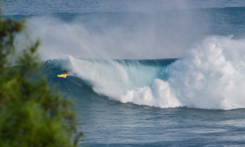 a person surfing on a yellow surfboard catching a massive wave in jaws, jaws 4k