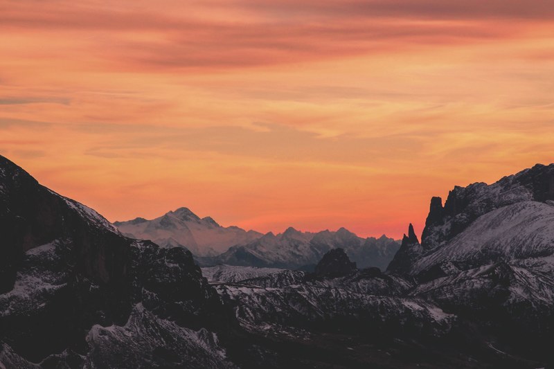 craggy snow covered mountains stretching to the horizon during sunset, sunset over mountains in seceda 4k