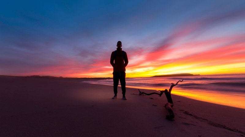 a male silhouette on a sydney beach during the late evening with a strong sun in the background, male silhouette sydney sunset 4k