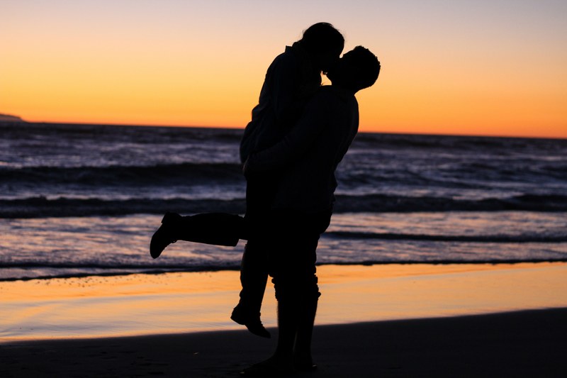 a couple kissing and embracing by the beach at sunset one lifting the other up, beach sunset sunrise and embrace 4k