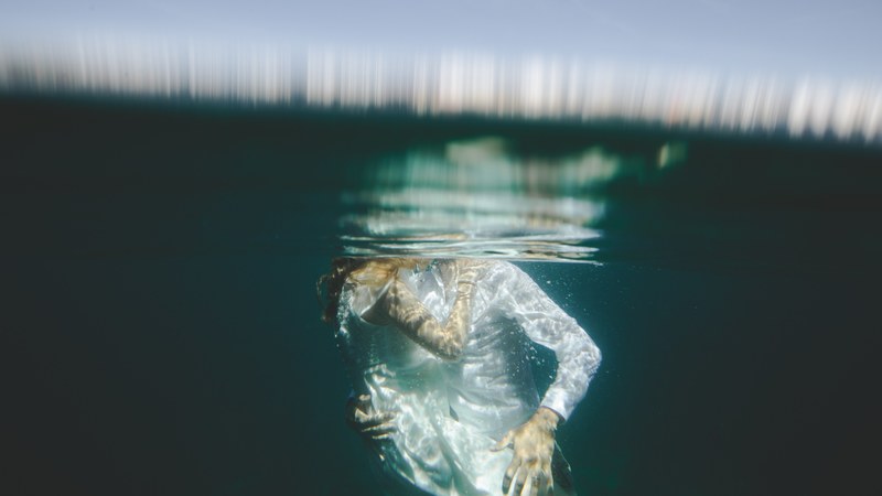 underwater photo of a bride and groom plunged below the surface sharing a kiss, newlyweds kissing underwater 4k