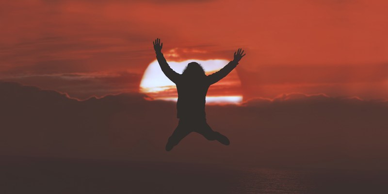 silhouette of person jumpin up mid air with red sky as the sun sets, fly 4k