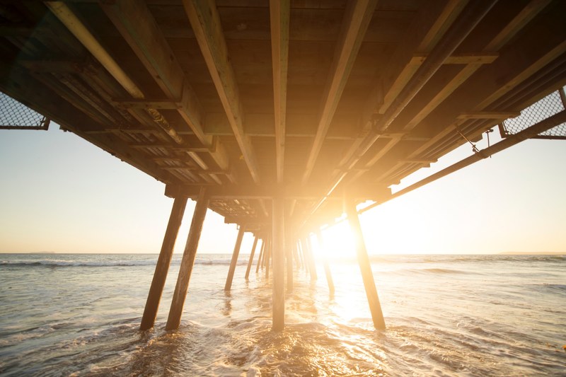 sunrise from below a san diego pier with sunlight reflecting on ocean, sunrise below pier 4k