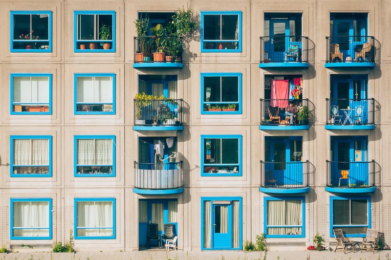 an apartment building with blue windows and balconies filled with plants in amsterdam bullewijk, amsterdam bullewijk apartment 4k