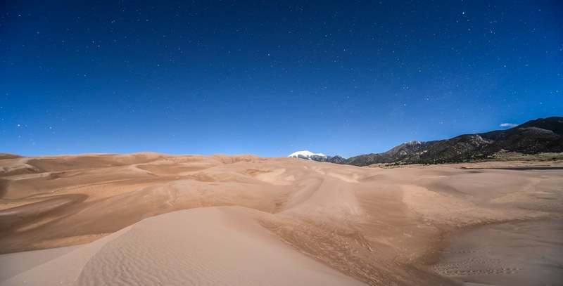 rolling sand dunes form a trail in the desert at dusk, clear desert night sky 4k
