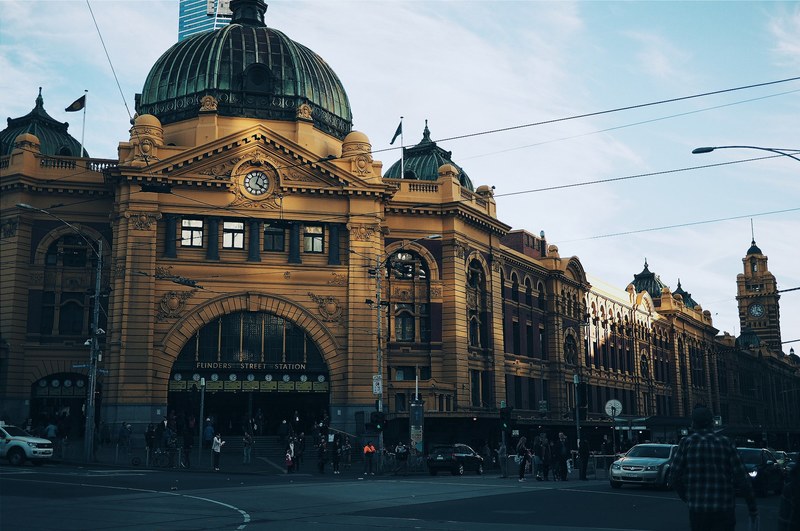 cars on driving on road in front of flinders street railway station on clear day, driving outside flinders street railway station 4k