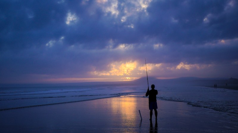 a silhouette of a fisherman fishing on a beach on kiawah island in the evening, fisherman on an evening 4k