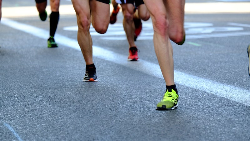 a shot of peoples feet as they run on pavement, _marathon runners feet close 4k