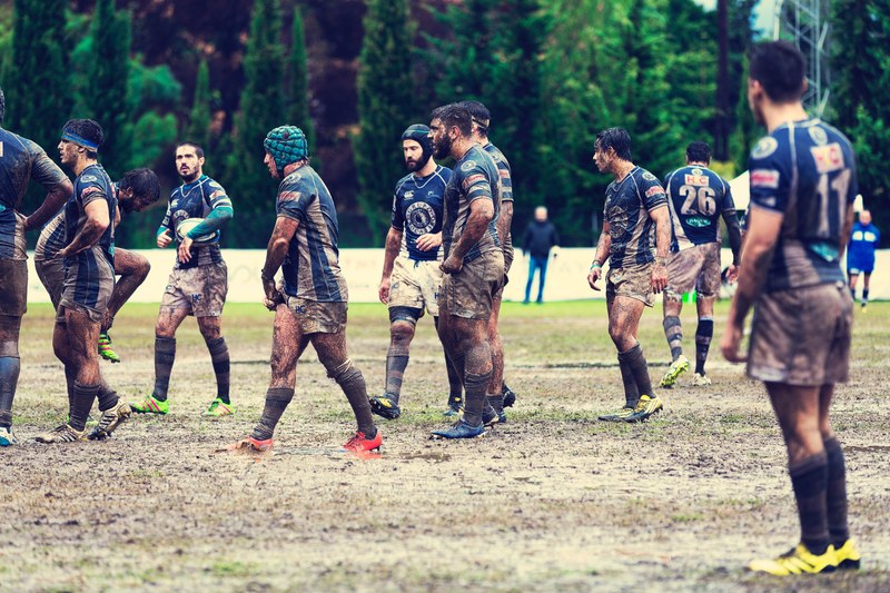 a male rugby team covered in dirt and mud on a field during a game, rugby 4k