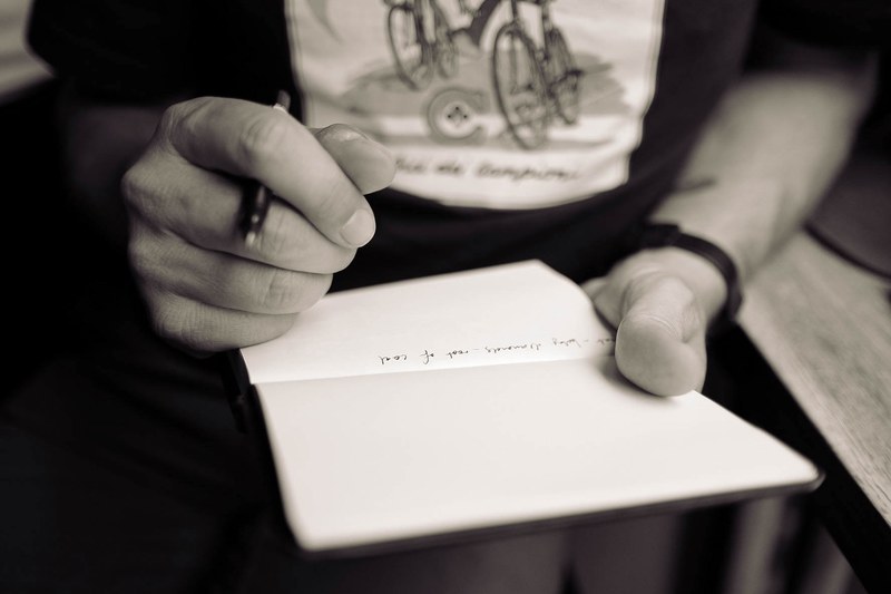 a desaturated shot of a person writing on a blank page, filling a blank page 4k