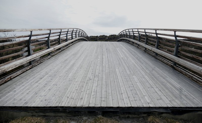 a curved wooden bridge leading into a town, curved wooden bridge 4k