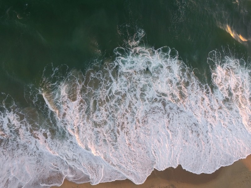 drone aerial view of the ocean foam washing on the huntington beach california united states, ocean foam drone view 4k