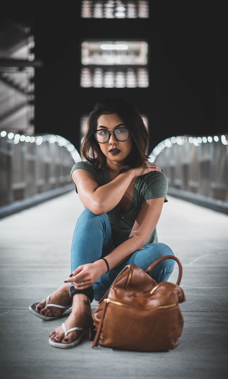 a woman with dark hair and eyes wearing dark lipstick sitting on a lit up bridge, angel wings 4k