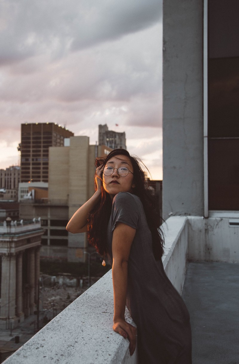 an asian girl leaning over a balcony ledge, _asian girl balcony ledge 4k