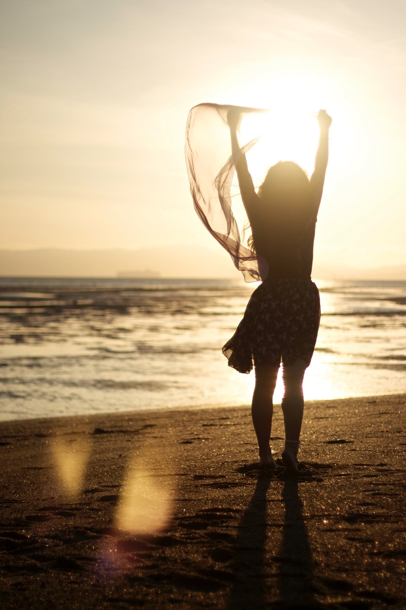 woman with a scarf raising hands on the alameda beach, taking in the sea 4k