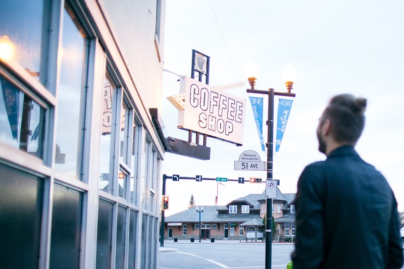 a guy with a man bun standing outside of a coffee shop on 51 ave in red deer, red deer coffee shop 4k