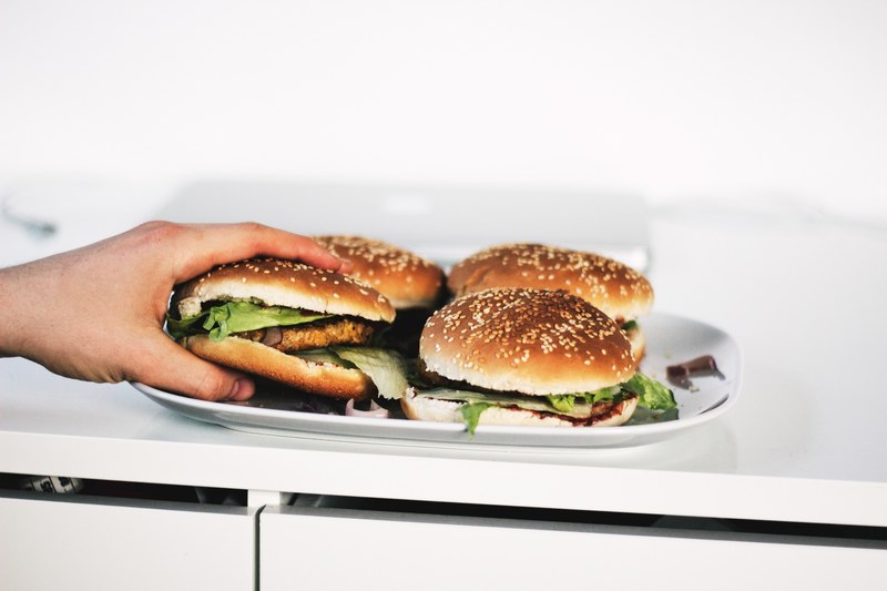 a person grabbing a burger from a plate full of hamburgers, burgers for dinner 4k