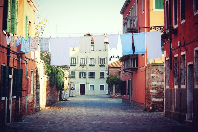 street view of colorful houses with clotheslines full of drying clothes across the street, colorful houses 4k
