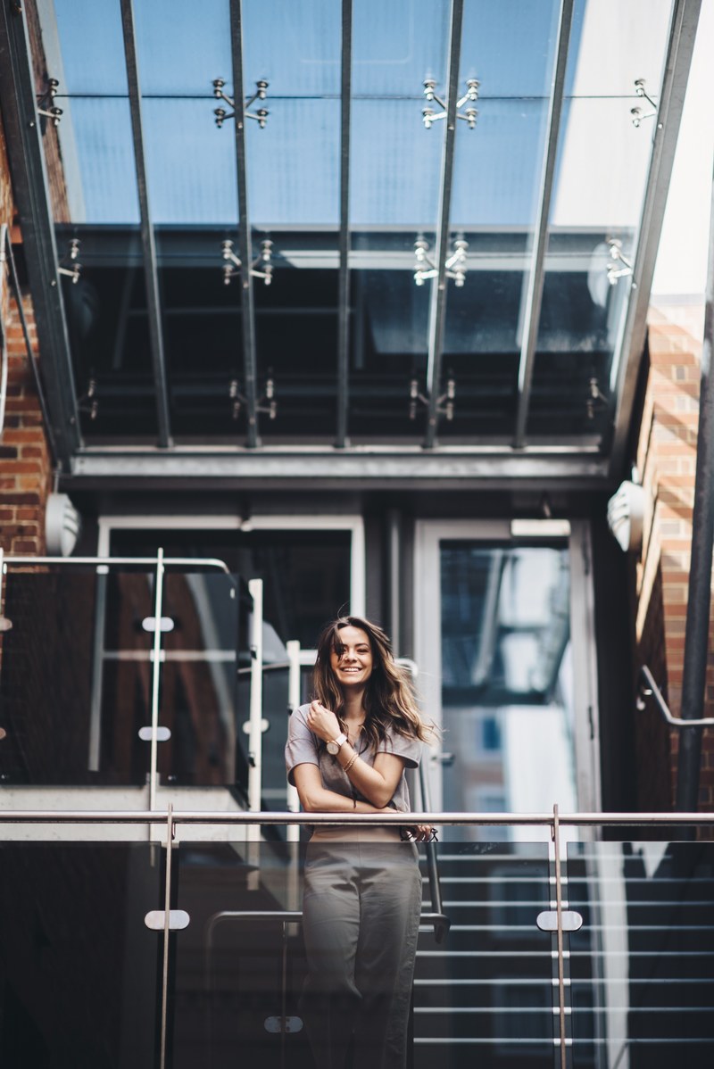 a laughing woman stands behind a railing by the stairs in a perth building, woman behind railing in perth 4k