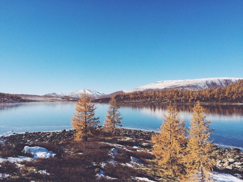 the calm landscape in autumn of trees and snowy mountains across the lake at buryatia, lake at buryatia 4k