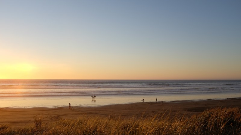 view of the calm ocean horizon and a sandy beach during sunset at ninety mile beach, ocean coast at sunset 4k