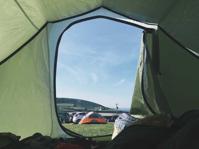 the view of a campsite and clear blue sky from inside of a green tent, morning sunshine 4k