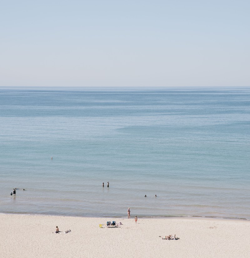 view of the swimmers on the sandy beach of the calm ocean, sand beach by the calm ocean 4k