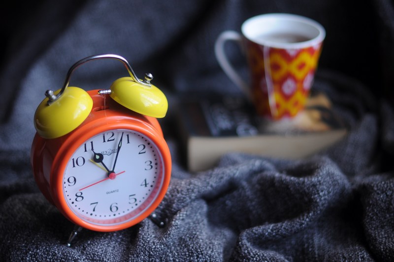 a macro shot of a standard alarm clock cup of coffee and a large book, book coffee and clock mumbai 4k