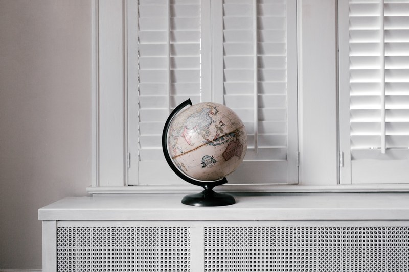 a cream colored globe of the earth sits in a in a completely white room, the remedy is travel 4k