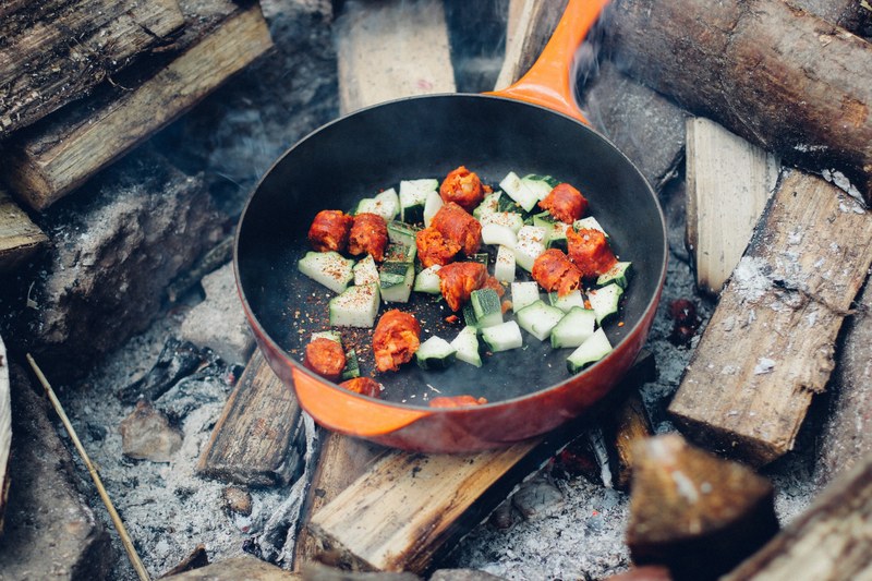 cooking vegetables in a skillet over a fire pit while camping, cooking while camping 4k