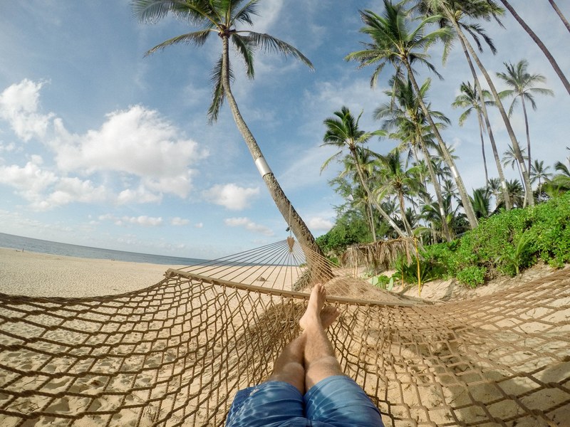 a person lying down in a hammock on the beach, _hammock beach luxury 4k