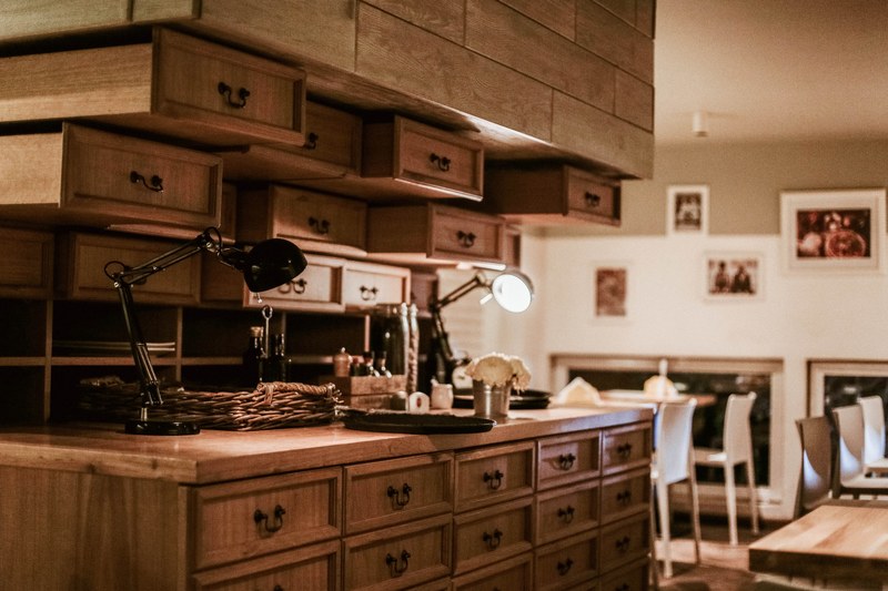 rows of wooden drawers surrounding a small workplace in middle of well lit room, well lit workplace 4k