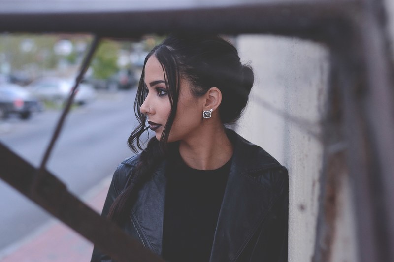 fashionable woman with dark makeup and hair leaning against a wall, dark makeup look 4k