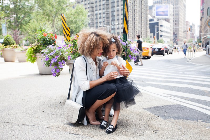 a mom and child both with curly hair cuddling in the street in new york, mom and daughter in new york 4k