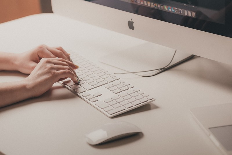a womans hands on a computer keyboard on a white workspace with an imac computer, writer at work 4k