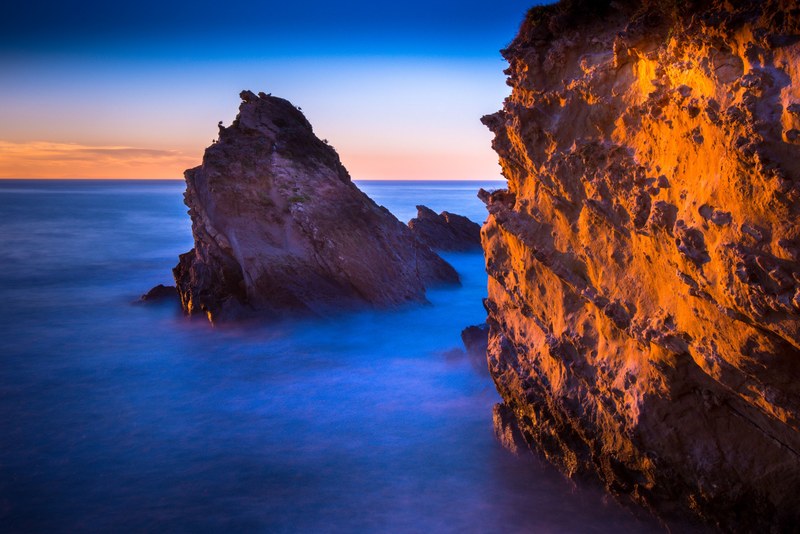 golden sunset reflecting on the rocky cliffs of biarritz that tower above the misty sea waters, golden crags of biarritz 4k