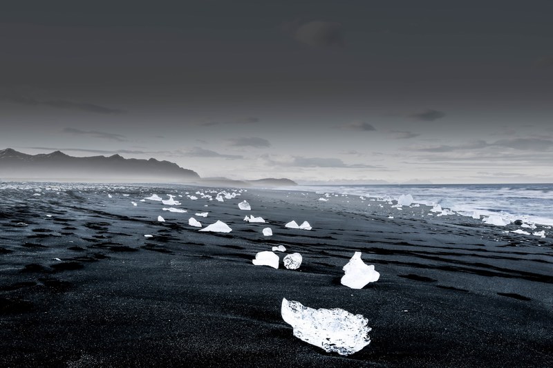 ice dots the black sandy beach of glacier lagoon, glacier scatter 4k