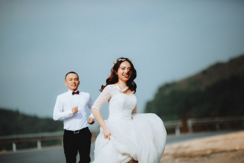 groom chases after laughing bride in vietnam with hills behind them, bride running from groom vietnam 4k