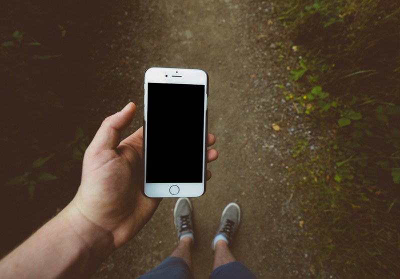 an overhead shot of a man holding a white iphone while walking on a dirt path, iphone in the wilderness 4k