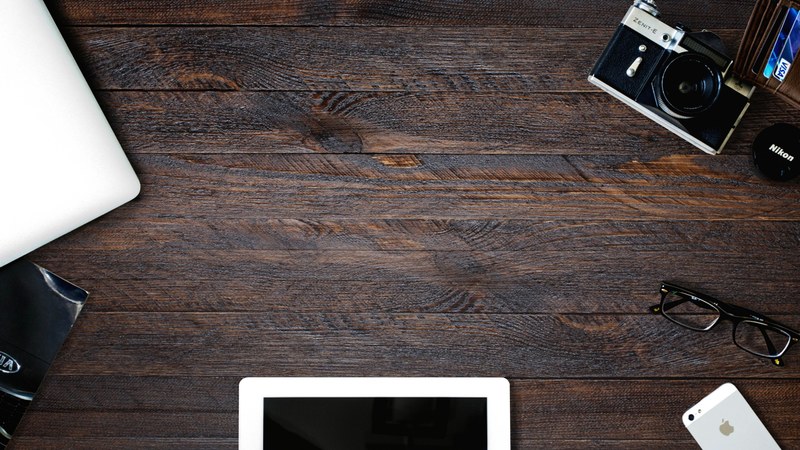 a flatlay with a tablet an iphone a vintage camera and a laptop on a dark wooden surface, creative flatlay on dark wood 4k