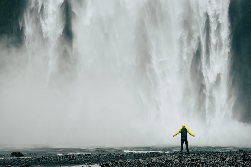 person with outstretched arms basks in the mist of a waterfall, at the waterfall 4k