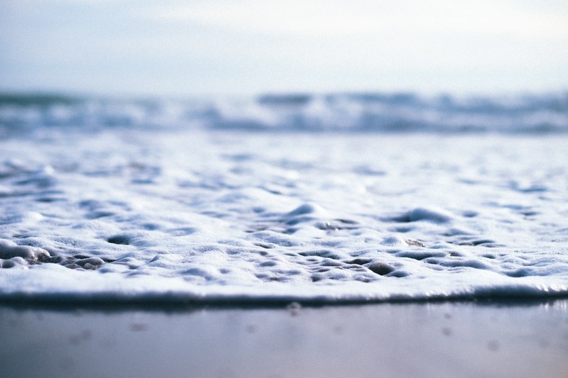 closeup shot of the sand and sea as the water foams up taken in sunset state beach, sea foam 4k