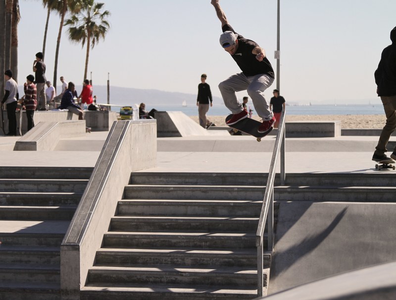 skater in mid air above the stairs and a rail at venice, drop in 4k