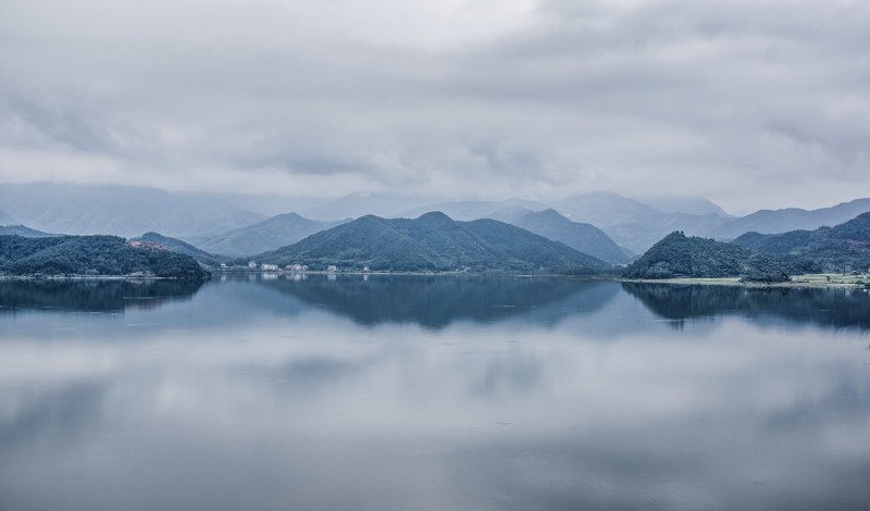 view from a calm lake on its hilly shores, green lakeside 4k