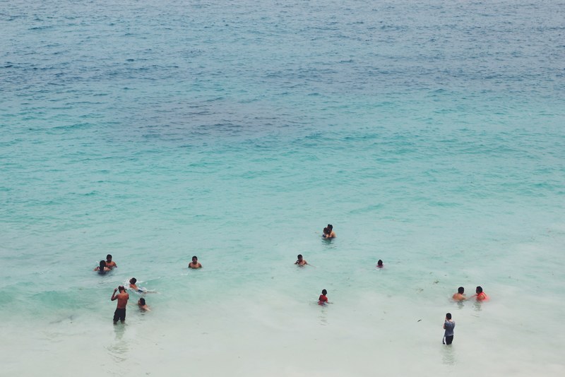 a diverse group of people stand play splash and swim in the blue waters of the ocean, people enjoy the water at the beach_ 4k