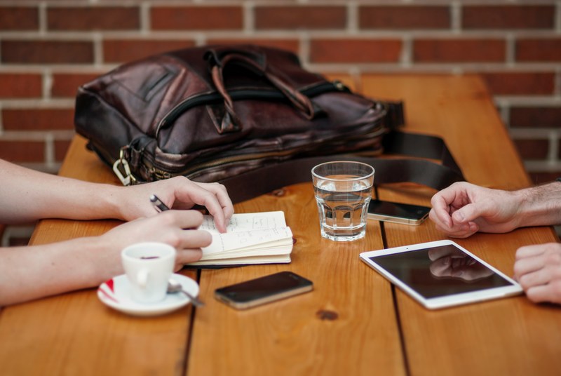 two people having a meeting while displaying their iphone ipad and smartphone on the table, _two people meeting with iphone and ipad 4k
