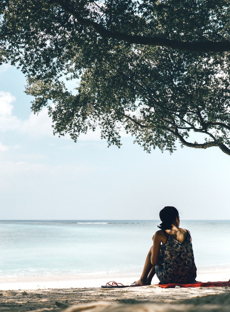 woman sitting on a sand beach under the tree, woman sitting on the beach 4k