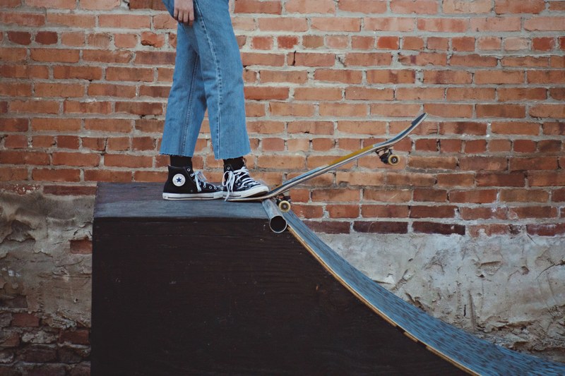 kid in jeans and converse sneakers stepping on skateboard on a ramp edge in augusta common, skater kid in augusta common 4k