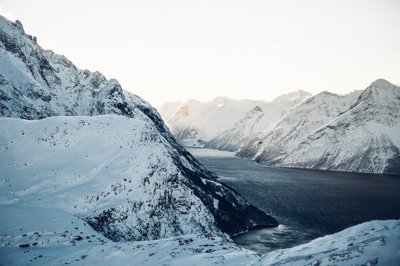 dark lake runs through the valley of a snowy mountain range, norway fjord 4k