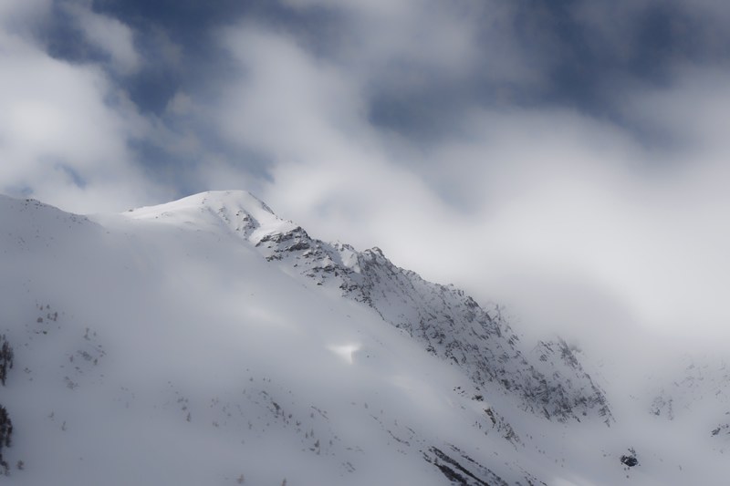 clouds cover a snowy mountain ridge, fog rolling down a snowy mountain 4k